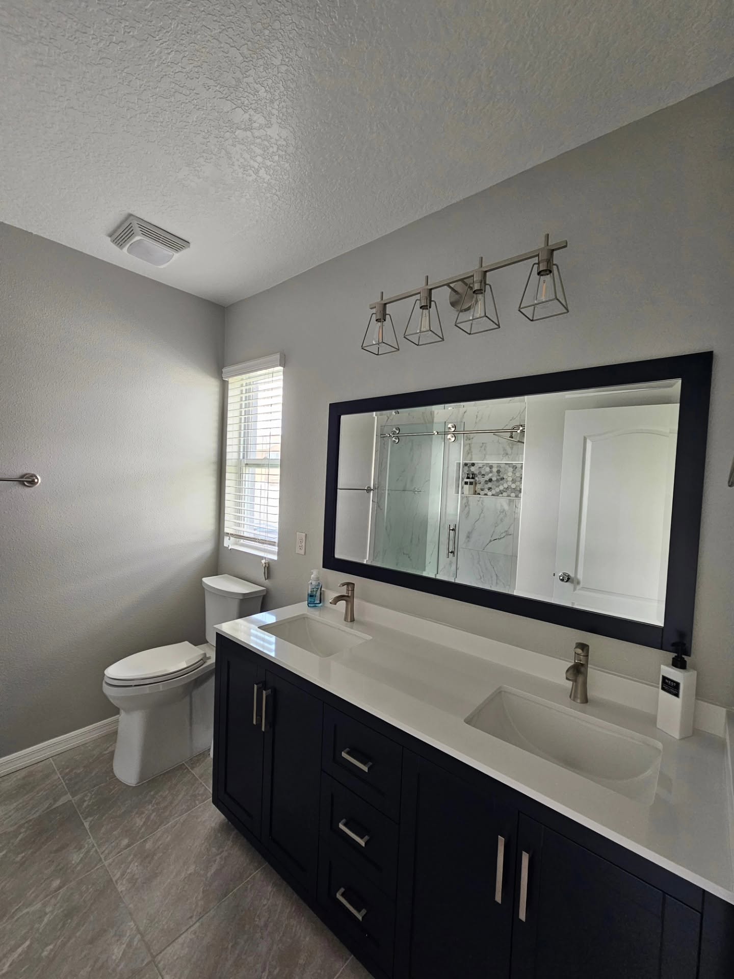 Bathroom vanity with black cabinets, double sinks, and a wide mirror