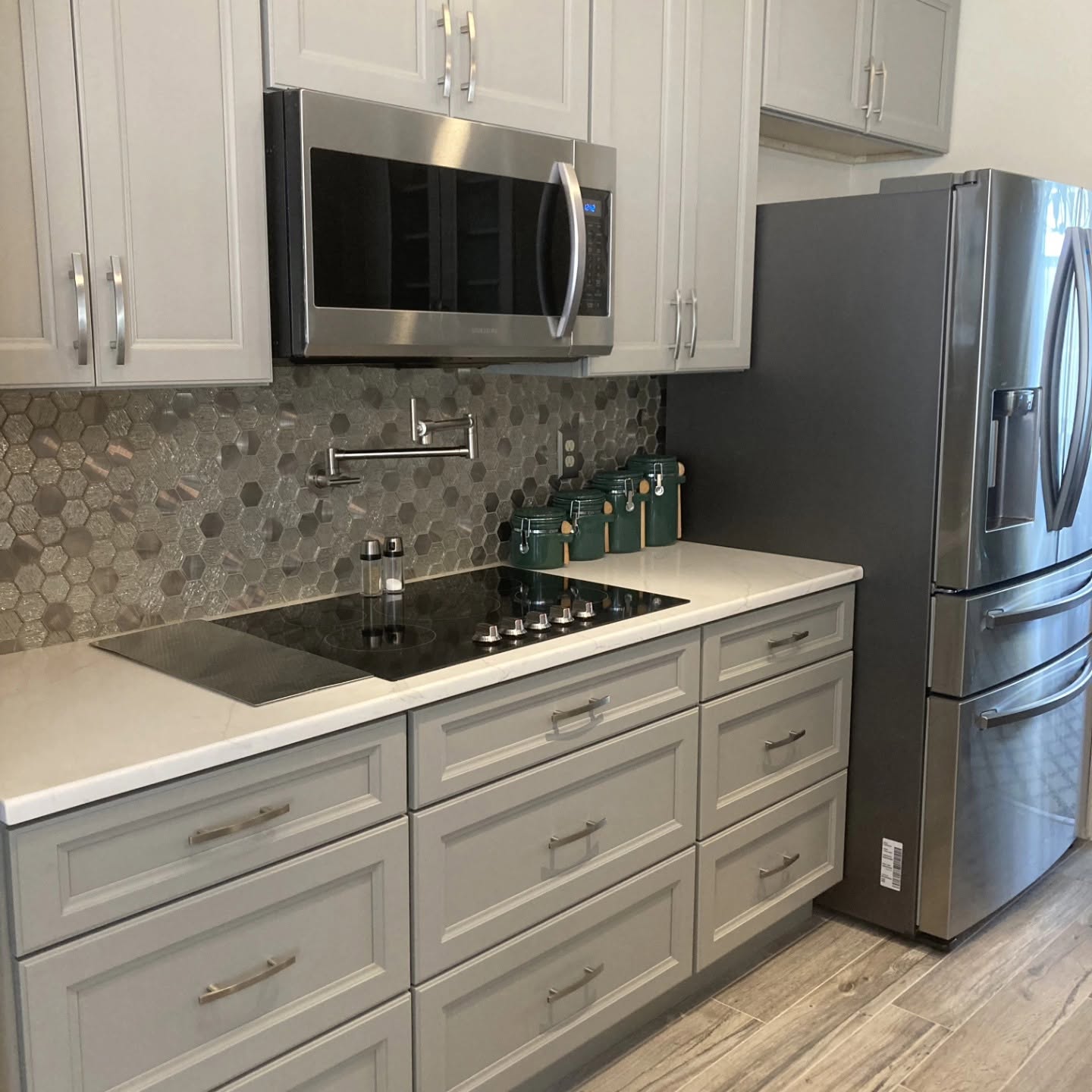 Kitchen backsplash with hex tile behind a cooktop and microwave