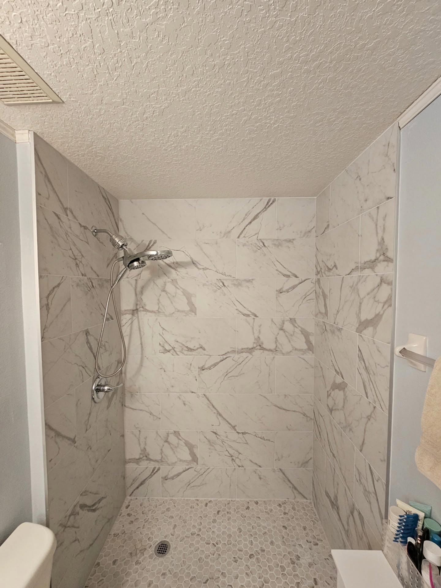 Walk-in shower with large gray wall tile and stone shower floor